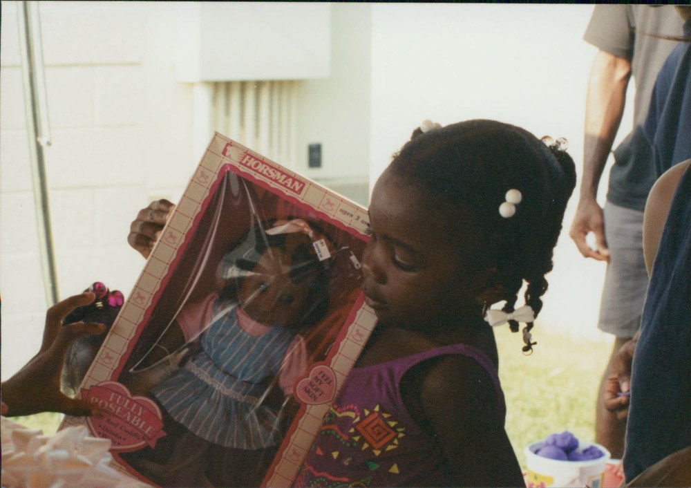 A young girl holding a boxed doll, looking closely at it
