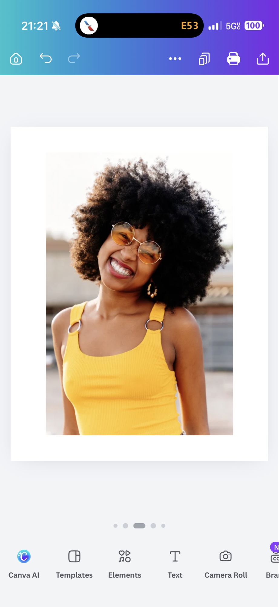 A smiling Black woman with an afro wearing a yellow tank top and gold sunglasses
